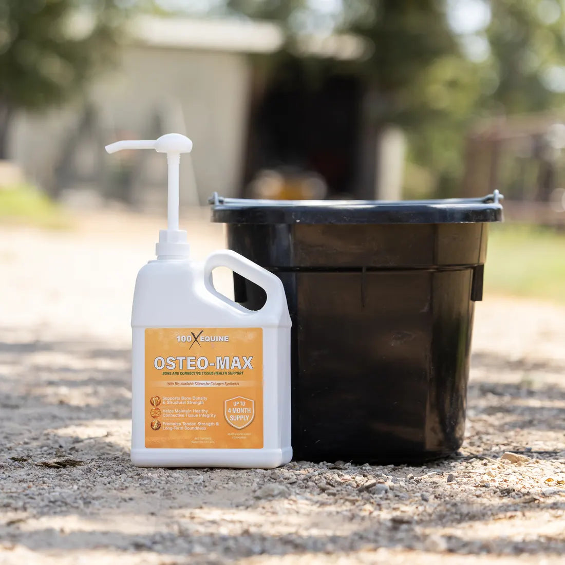 The Osteo-MAX gallon standing beside a black feed bucket in the barn aisle